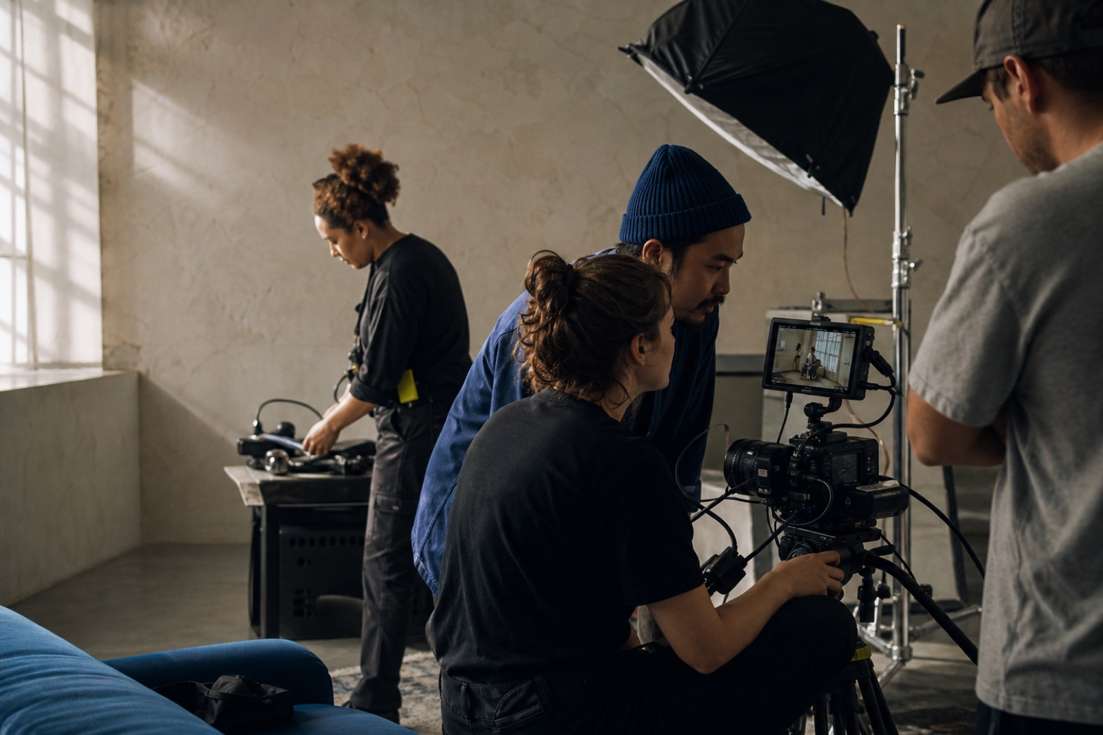 A small creative team reviewing a shot around a cinema camera in a studio